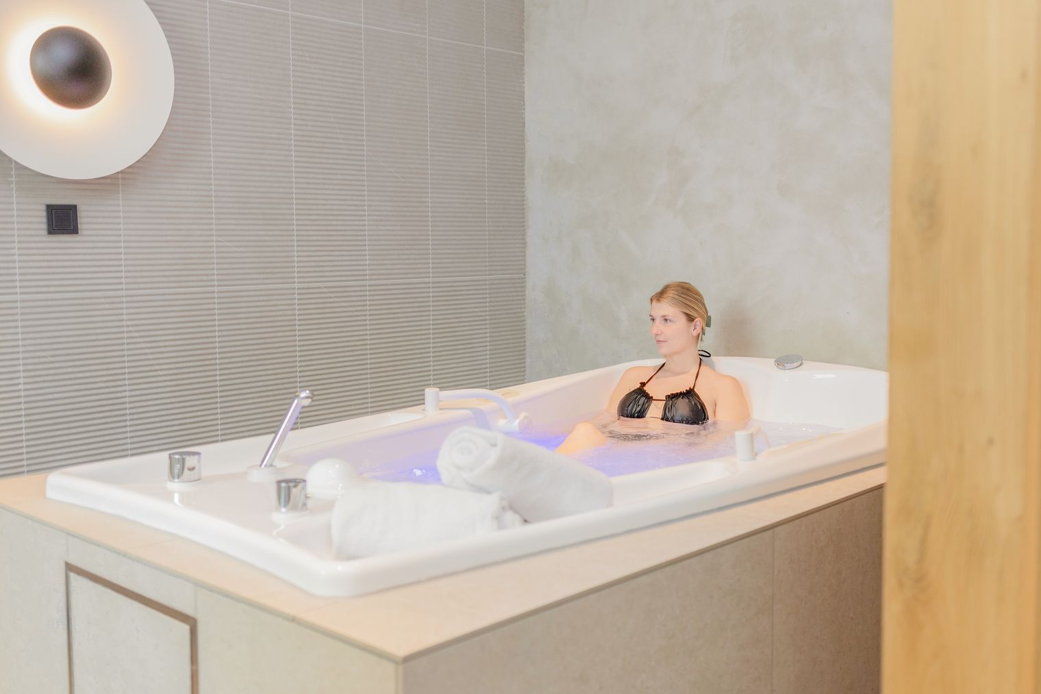Eine Frau liegt in der Doppel-Badewanne des Private Spa.